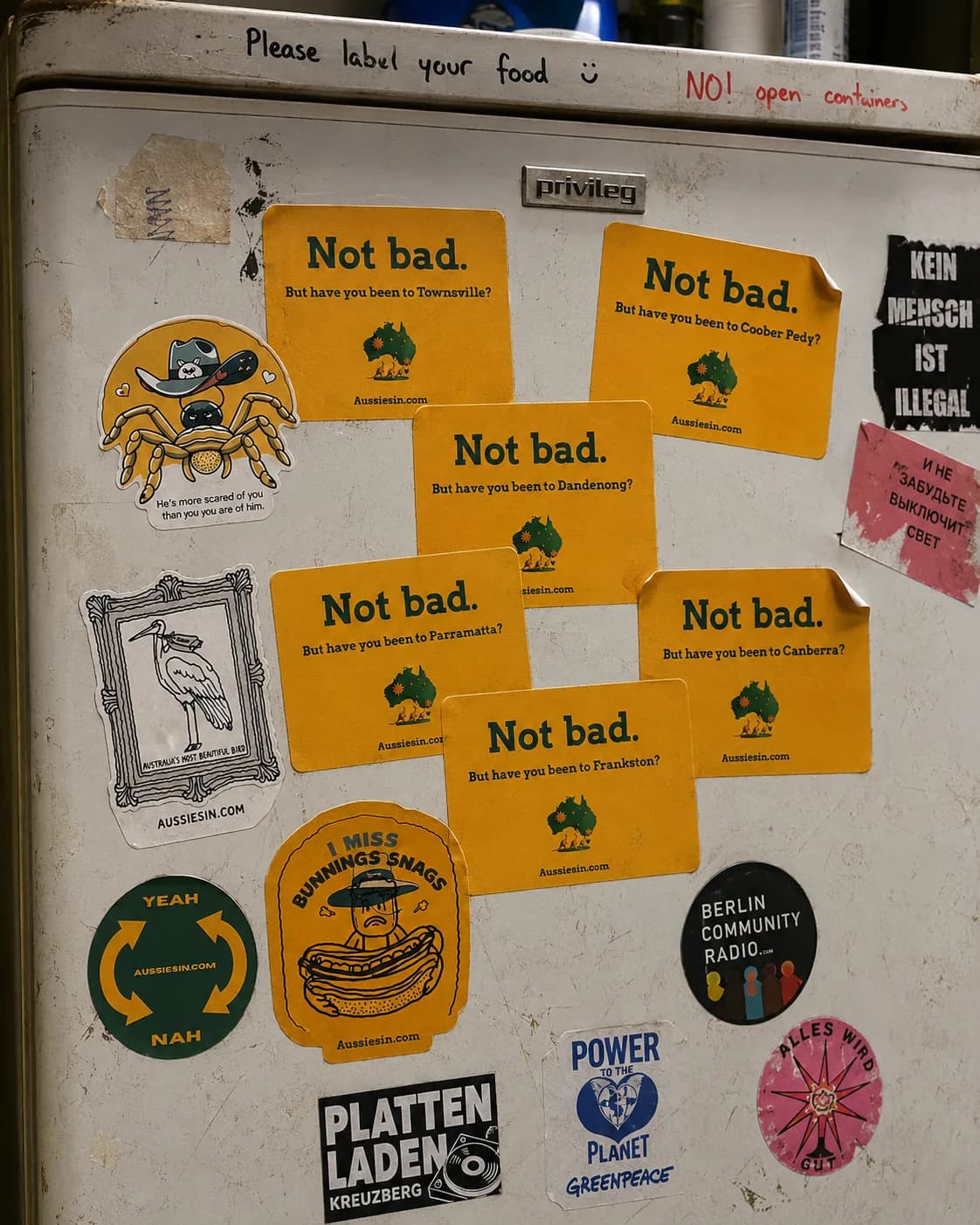 Aussies In stickers covering a Berlin hostel fridge among Berlin Community Radio, Plattenladen Kreuzberg, Power To The Planet and Russian-language stickers
