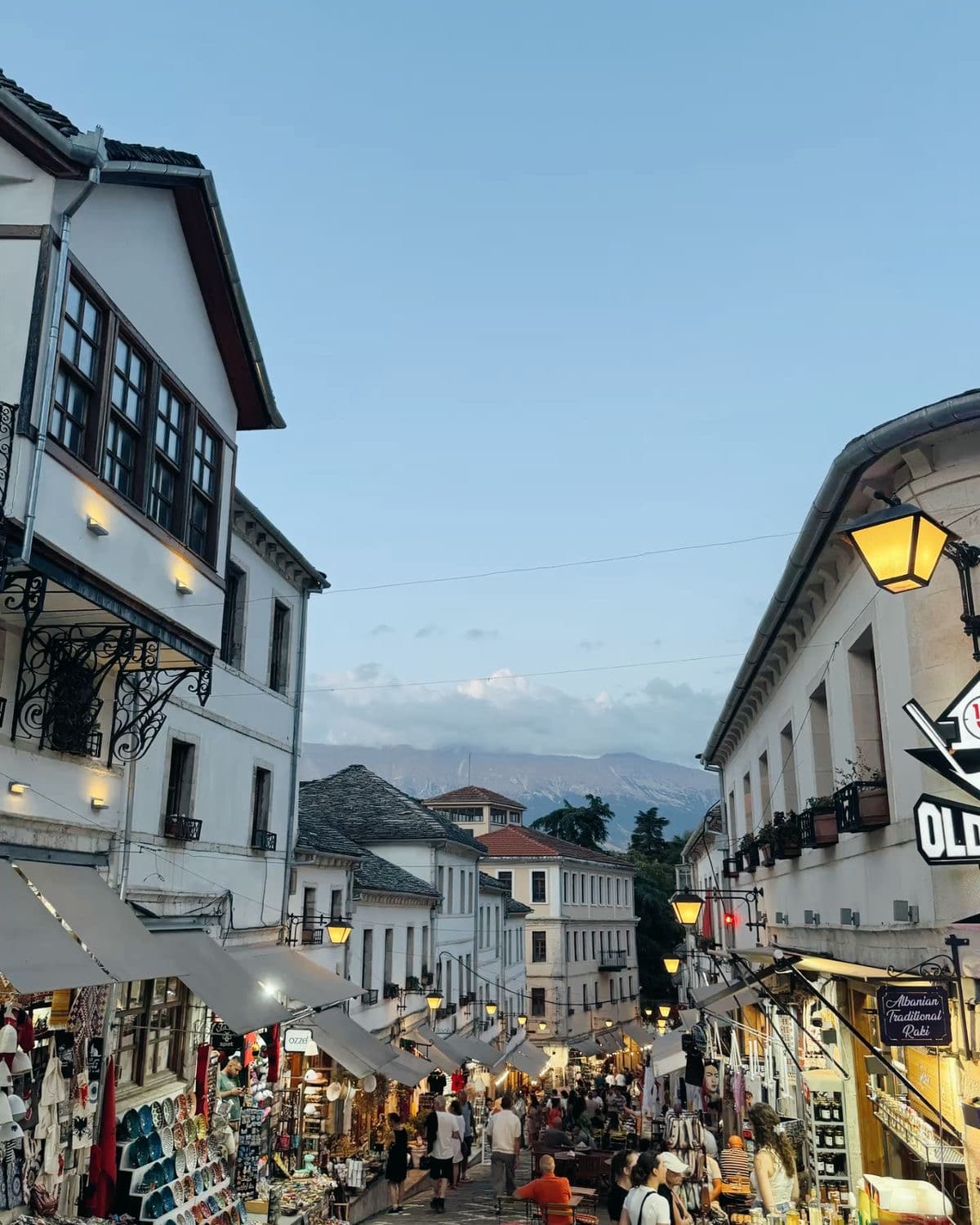 Gjirokastër at dusk — Ottoman stone houses, lit lanterns, market street.