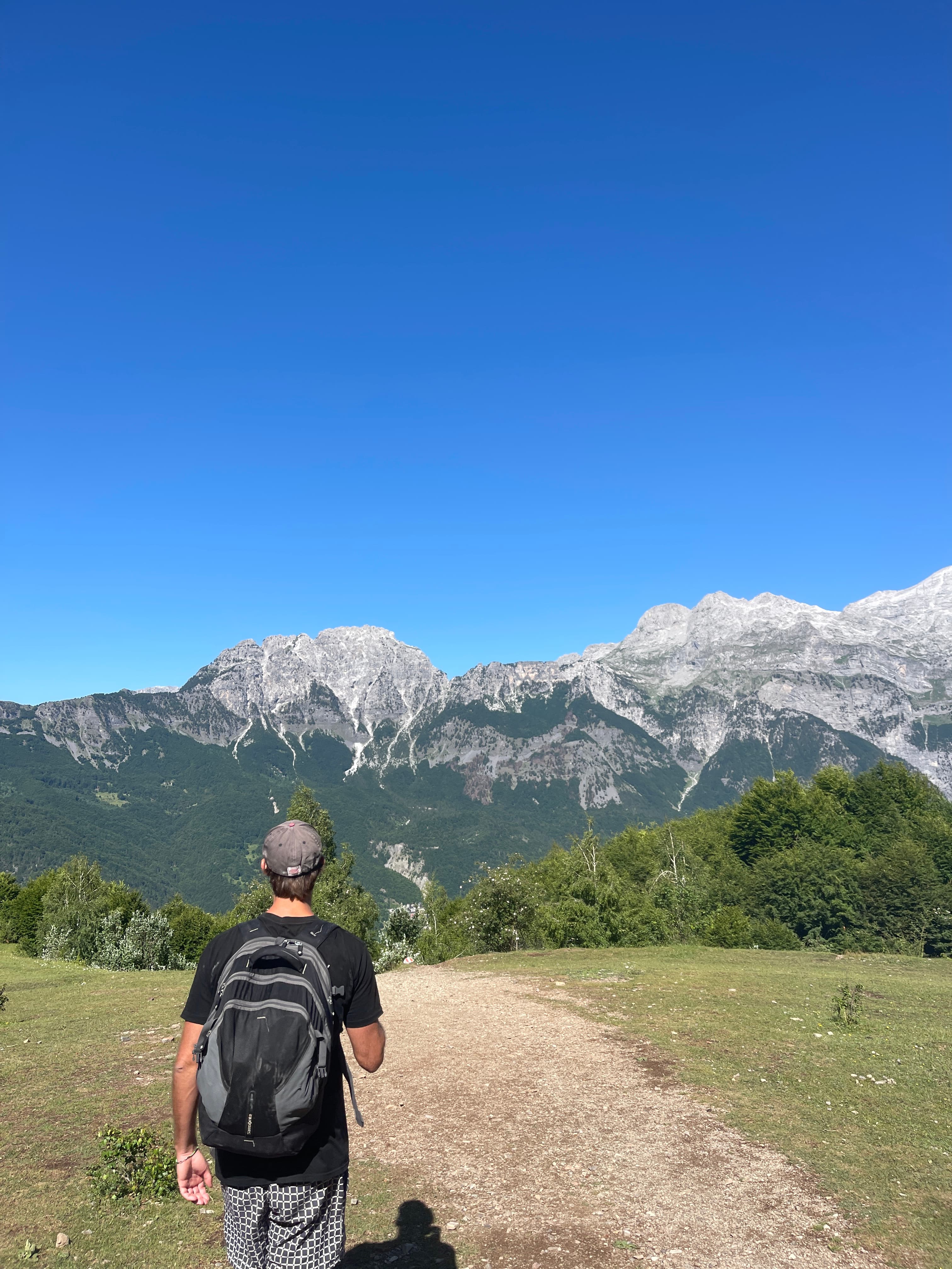 The Theth-to-Valbona hike — a walker on the trail with the Accursed Mountains behind.