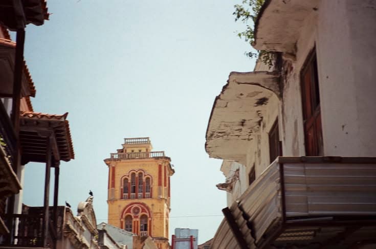 A yellow Cartagena tower with Moorish-arched windows framed by the terracotta rooftops of the Caribbean old town.