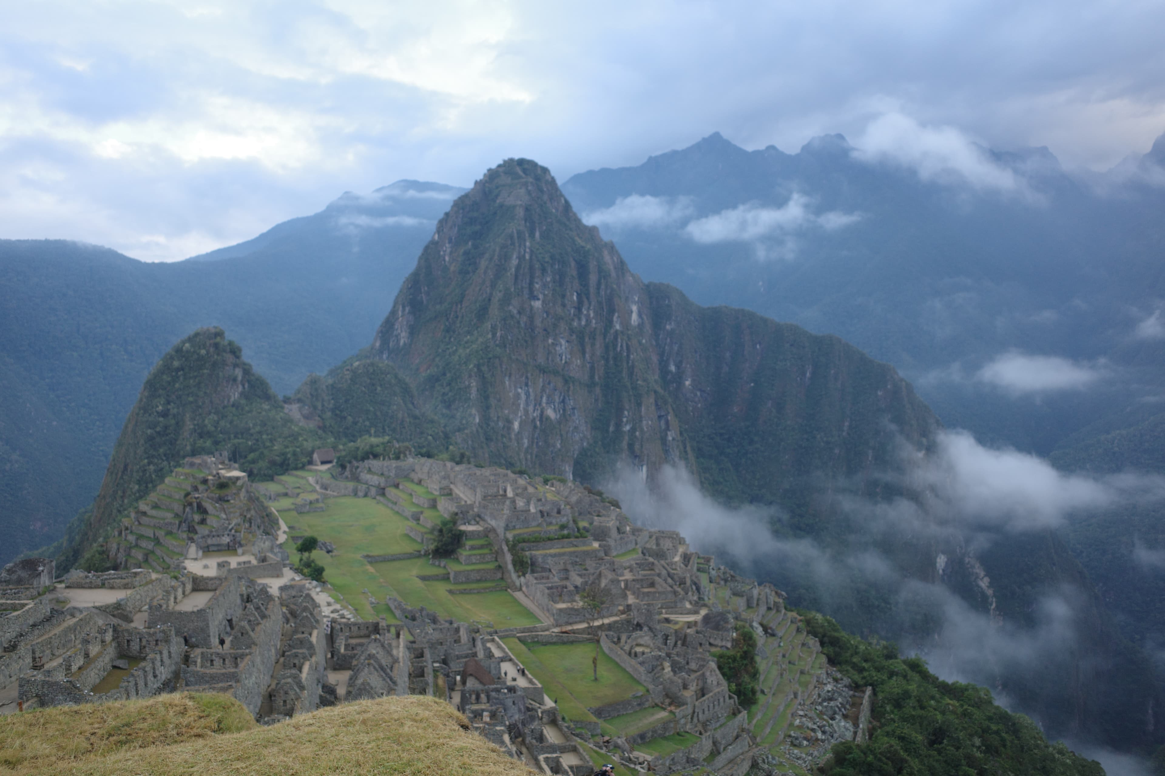 Machu Picchu at dawn — Inca terraces, ruins, mist lifting off the Andes.
