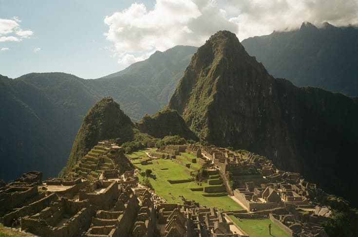 Machu Picchu at dawn — Inca terraces and ruins, mist lifting off the Andes.
