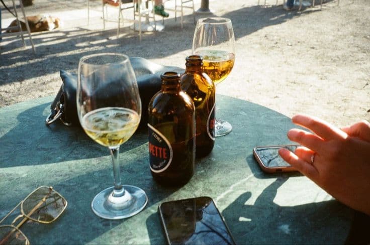 An afternoon on a Spanish terraza — glasses of cold white wine and beers sweating on a green marble table, sunglasses and phones, the golden light of a long lunch turned into the afternoon.
